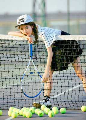 网球少女运动装球场上展示青春活力
