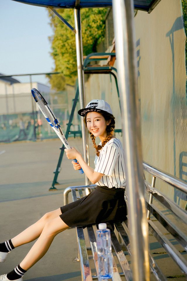 网球少女运动装球场上展示青春活力